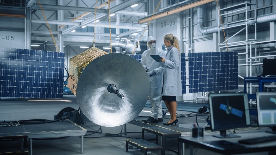 Female Chief Engineer talk to Technician while he is Working on Satellite Construction. Aerospace Agency Manufacturing Facility: Scientists Build, Assemble Spacecraft for Space Exploration Mission