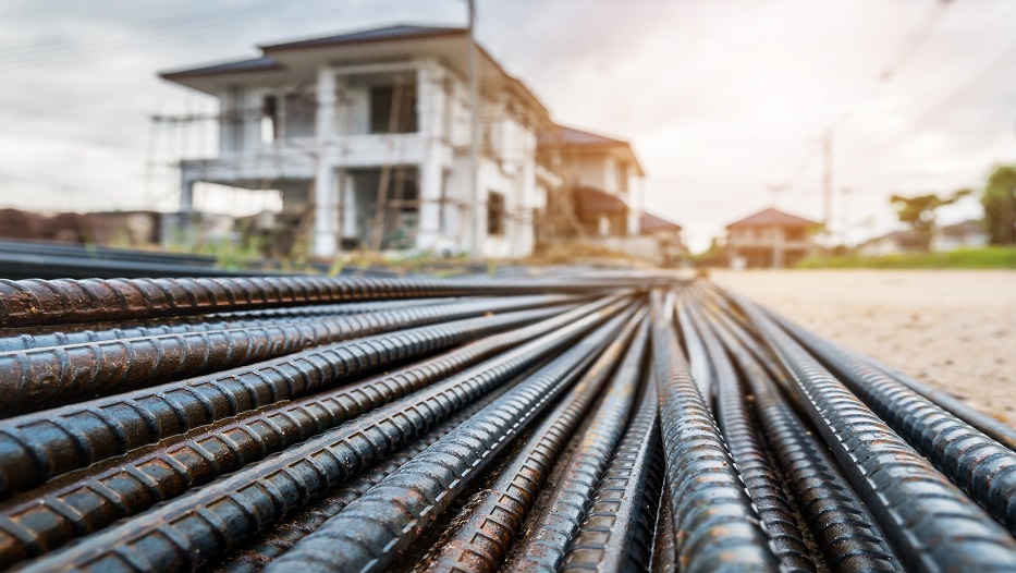 steel rebar for reinforcement concrete at construction site with house under construction background