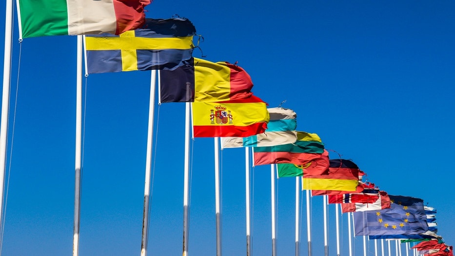 Flags of EU countries on a white flagpoles against a blue sky_MAPFRE Global Risks